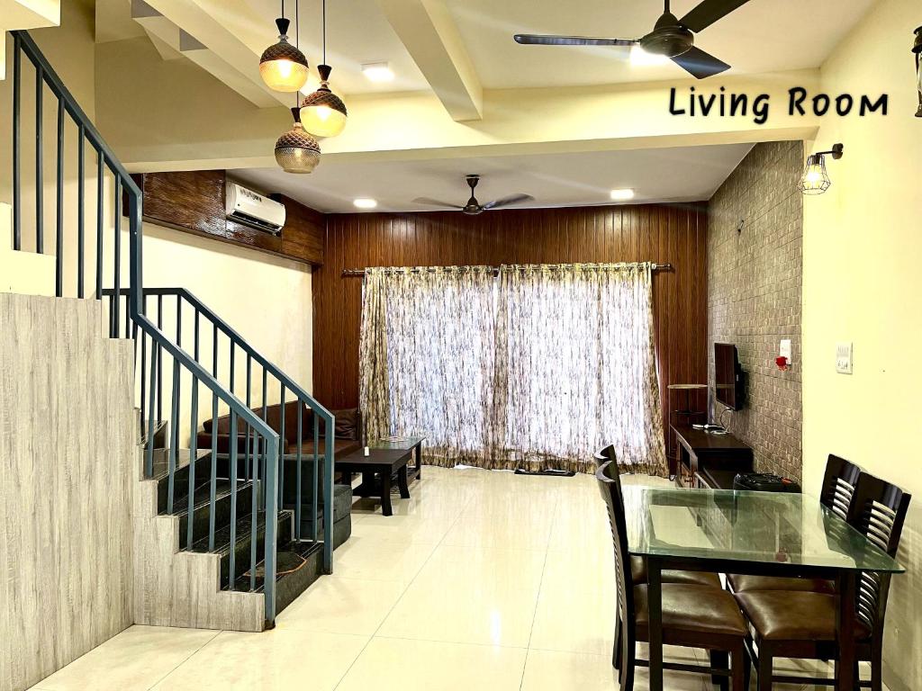 a living room with a dining room table and a staircase at Candy Stay's 2BHK with Pvt Pool in Lonavala