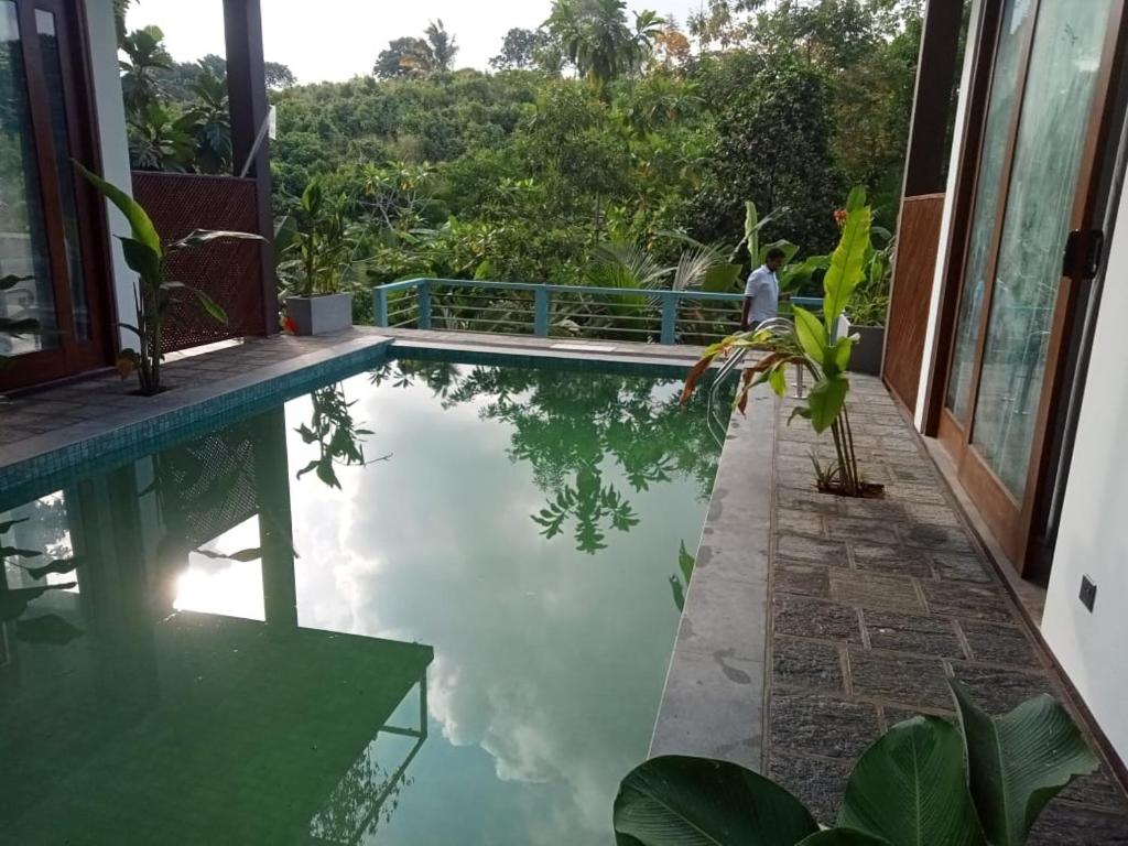 a pool with a man standing next to a house at Moon Lanka Hotel in Hikkaduwa