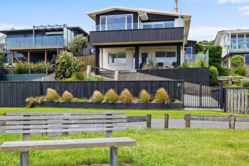 a wooden bench in front of a house at Wow On Wanaka Bay - beachfront living at its best in New Plymouth