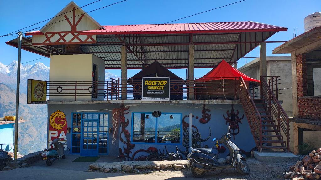 un edificio con un balcone e uno scooter parcheggiato di fronte di Rooftop Campsite Munsyari a Munsyari