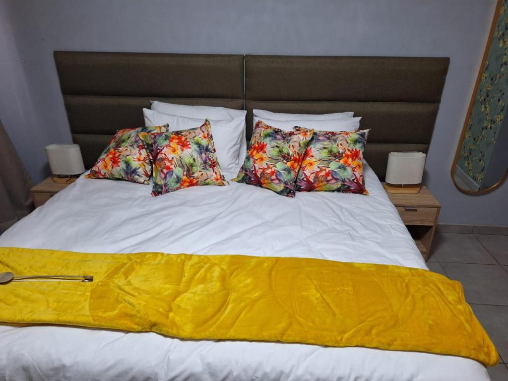 a bed with four pillows and a yellow blanket at 310 Bonnyvale in Kempton Park
