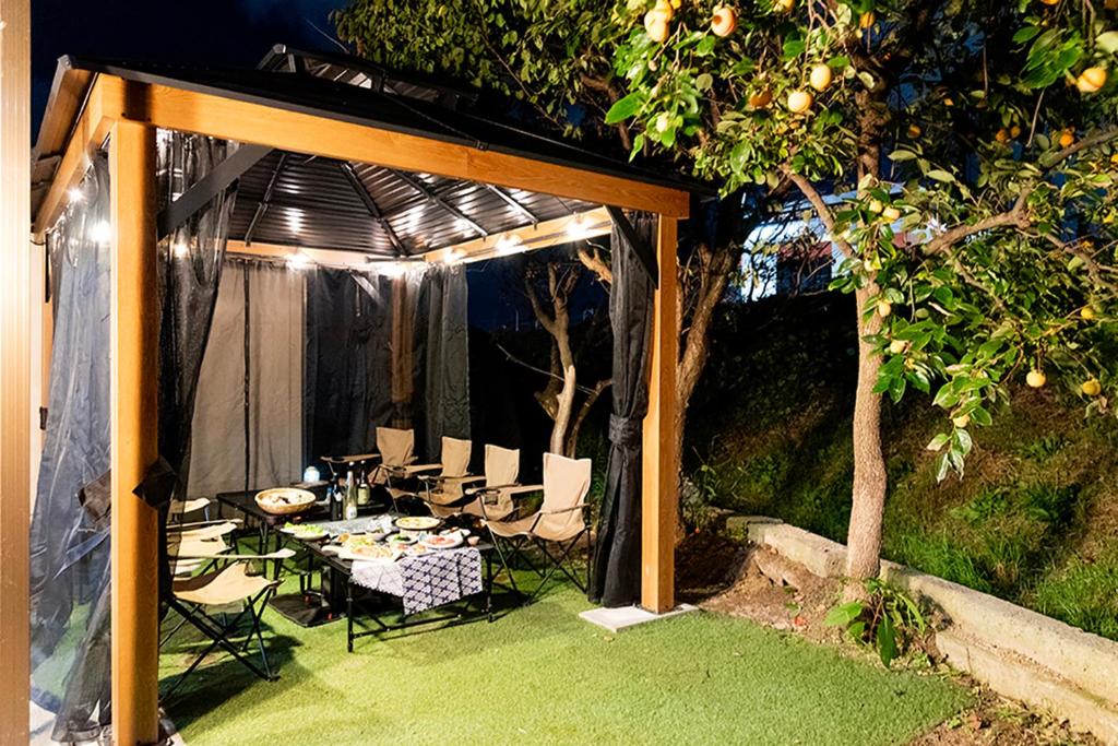 a gazebo with a table and chairs under a tree at f life house in Koriyama