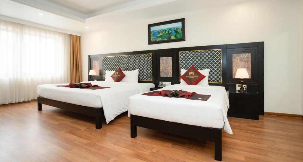 a bedroom with two beds with white sheets and red pillows at MT Collection Hotel Ha Long in Ha Long
