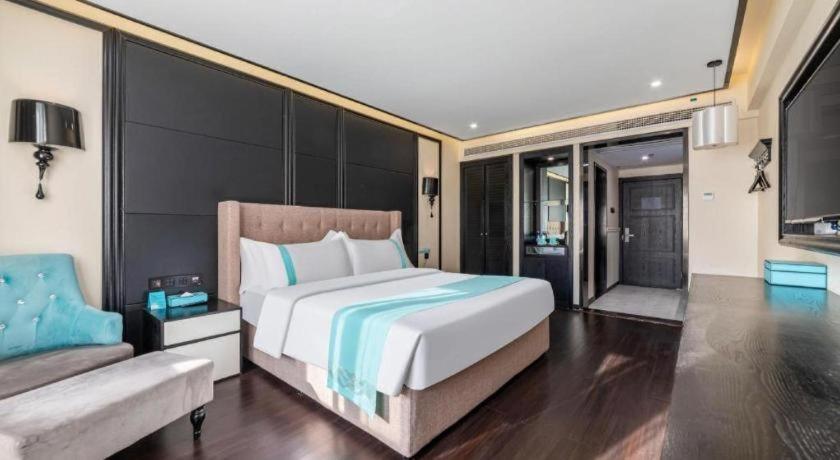 een slaapkamer met een groot bed en een bank bij Xana Hotelle Suqian Soho Ginza Branch in Suqian