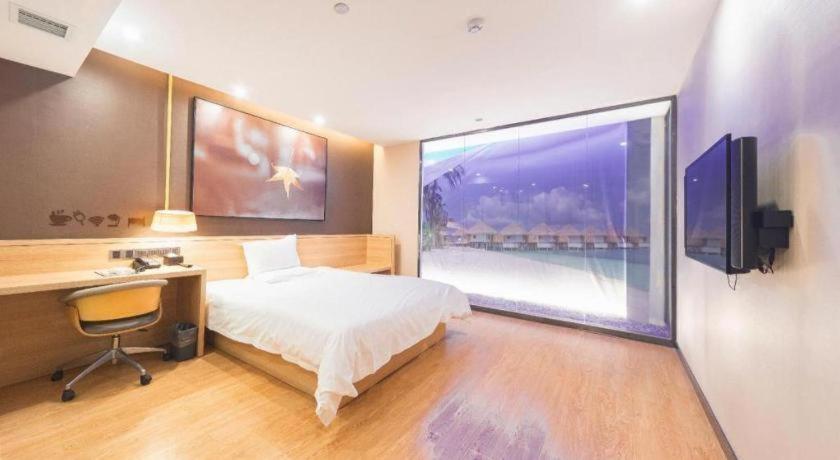 a bedroom with a bed and a desk and a large window at IU Hotel Changsha Railway Station Branch in Changsha
