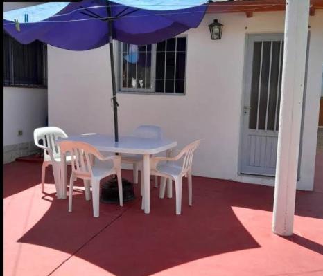 Una mesa y sillas con una sombrilla en un patio. en Departamentos Turísticos, en Cosquín