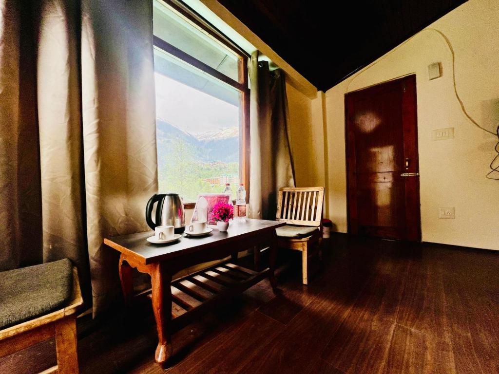 Una habitación con una mesa y una ventana grande. en Hotel Inn Way #Near Beas River, en Manali