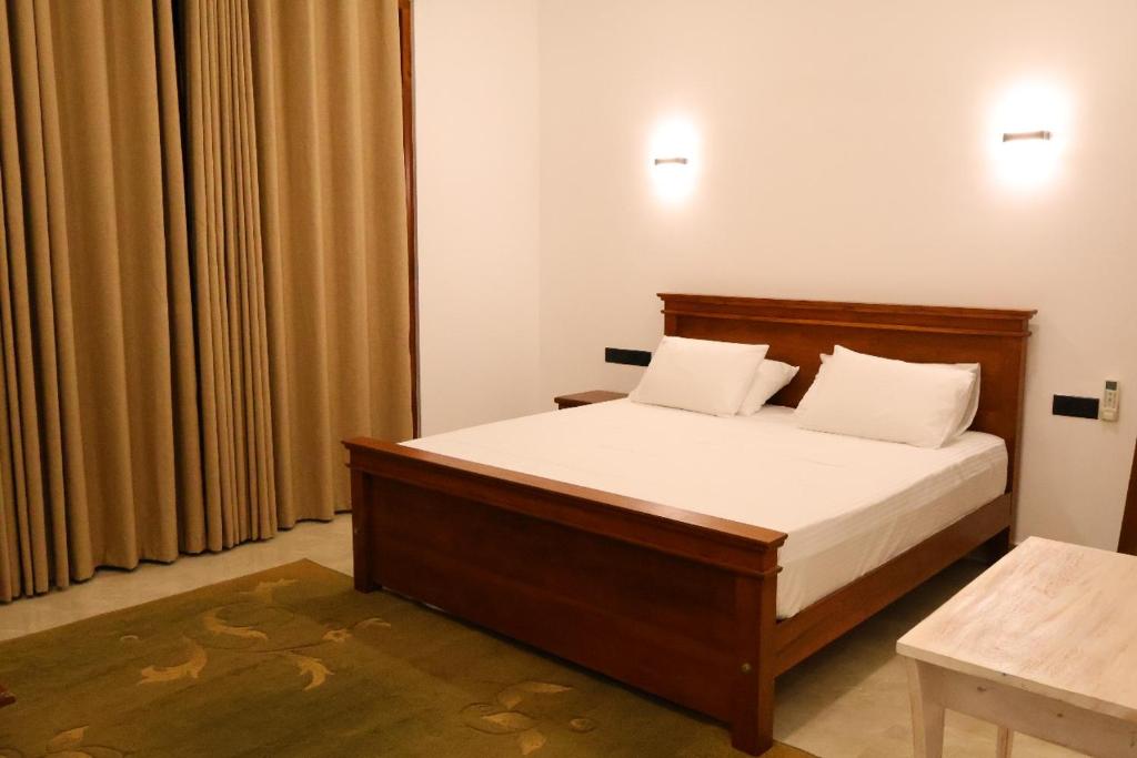 Schlafzimmer mit einem Bett mit weißer Bettwäsche und weißen Kissen in der Unterkunft Cinnamon Breeze Villa in Kandy
