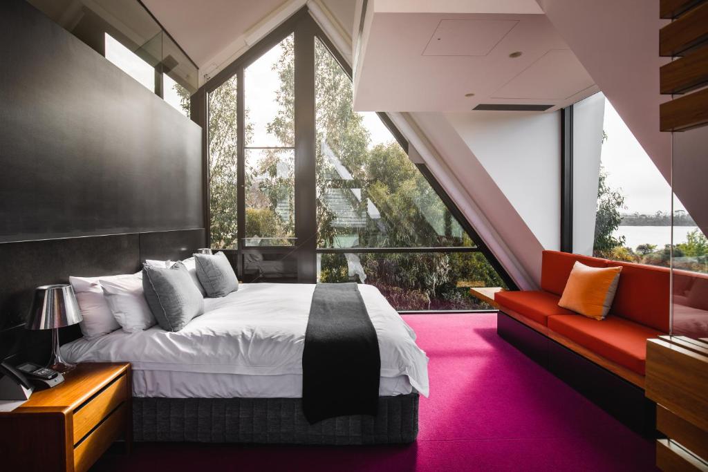 een slaapkamer met een groot bed en een rode bank bij MONA Pavilions in Hobart