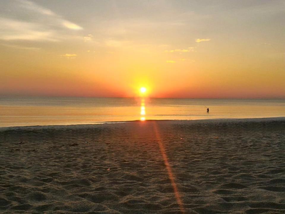 einen Sonnenuntergang am Strand mit einer Person im Wasser in der Unterkunft Beach Bar Hue Hostel in Hue