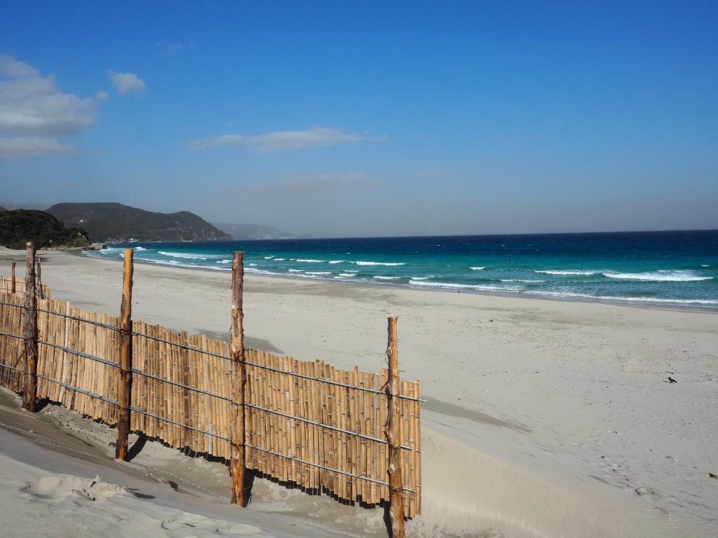 a wooden fence on a beach with the ocean at HealingDragon 　Sunrise house Shirahama in Shimoda