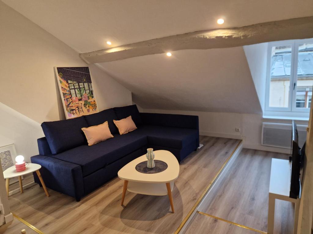 Una sala de estar con un sofá azul y una mesa. en Le grand logis de Meung Sur Loire, en Meung-sur-Loire