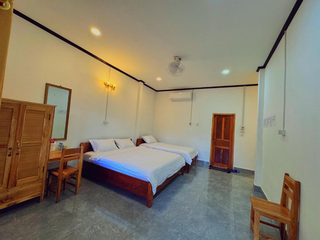 Un dormitorio con dos camas y una mesa y un espejo. en phoulisack2 guesthouse, en Nongkhiaw