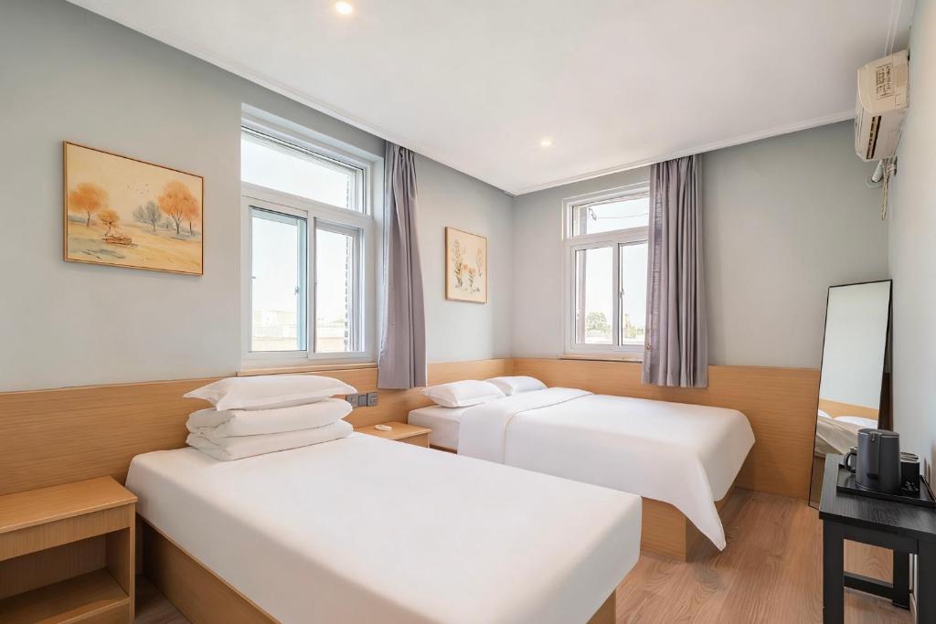 two beds in a room with two windows at Beijing Liangcang Hotel 10-minute walk to Tiananmen Square and the Forbidden City Free registration service for Tiananmen access 200 meters from the subway Beijing Cultural Hub Free coffee & free laundry service in Beijing