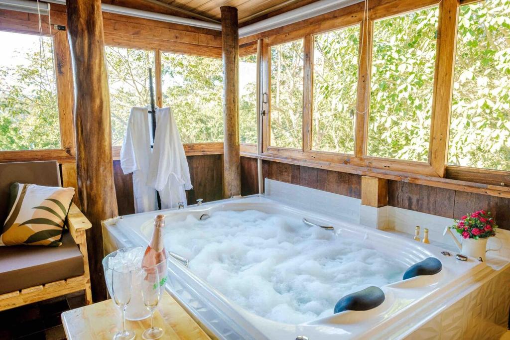 eine große Badewanne in einem Raum mit Fenstern in der Unterkunft Chalé romântico com banheira aquecida in Nazaré Paulista