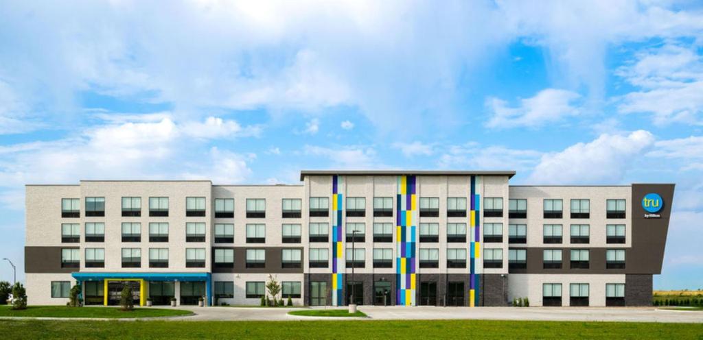 a white building with colorful poles in front of it at Tru By Hilton Grimes Des Moines in Grimes