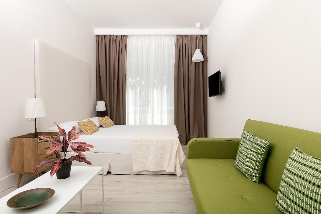 um quarto de hotel com uma cama e um sofá verde em Fuorlovado 40 em Capri