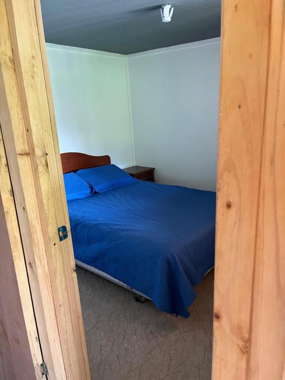 a bedroom with a bed with a blue comforter at Ancoa Lodge in Linares