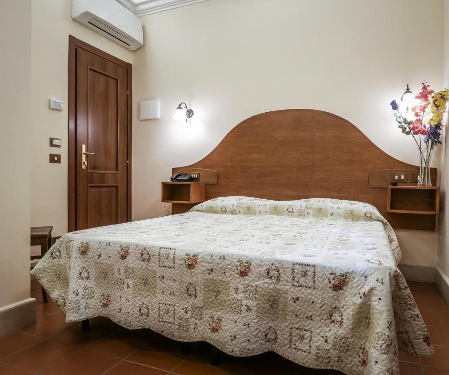 una camera con un grande letto con testiera in legno di Hotel 4 Coronati a Roma