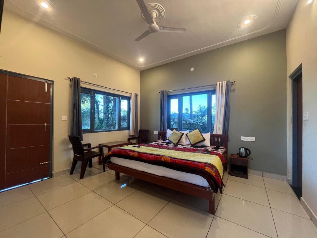 a bedroom with a bed and a desk and windows at 11 Gaon Homestay Lansdowne in Lansdowne