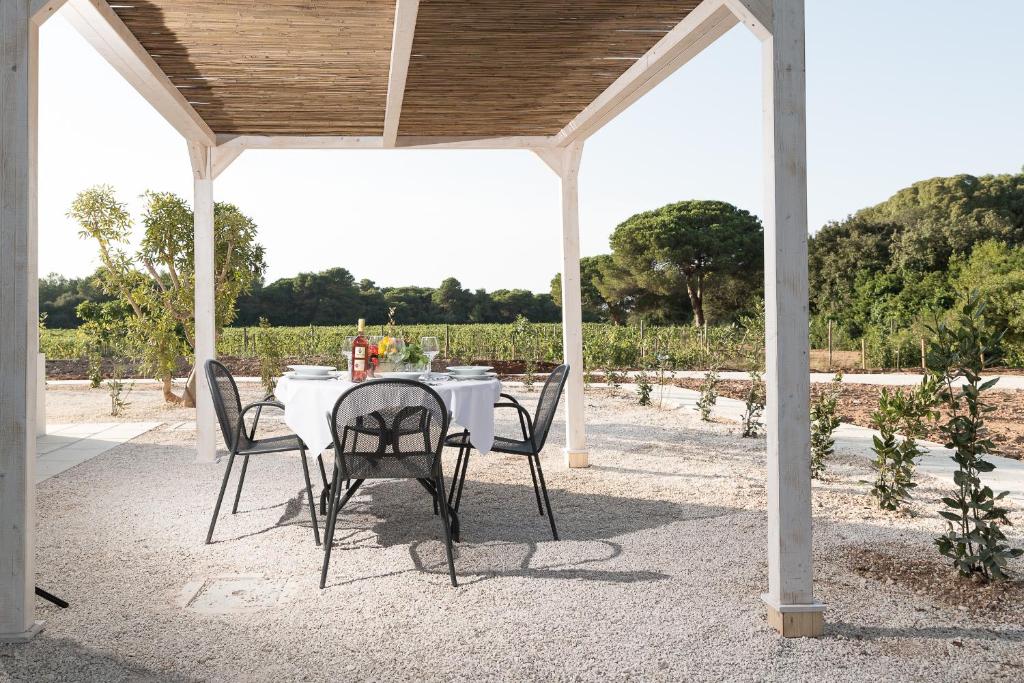 a white table and chairs under a pavilion with a view of a field at Masseria Mongiò dell'Elefante in Otranto
