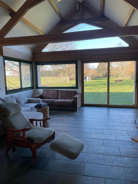 Maison Le Mans في Teloché: غرفة معيشة مع أرائك وكراسي ونوافذ