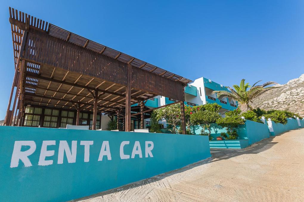 a building with a sign that reads rent a car at Alpha Studios in Arkasa
