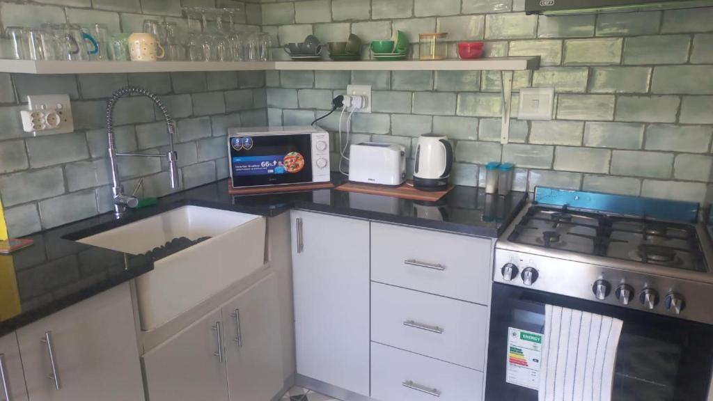 a kitchen with a counter with a stove and a sink at Unit 8 Hermanus Beach Club in Hermanus