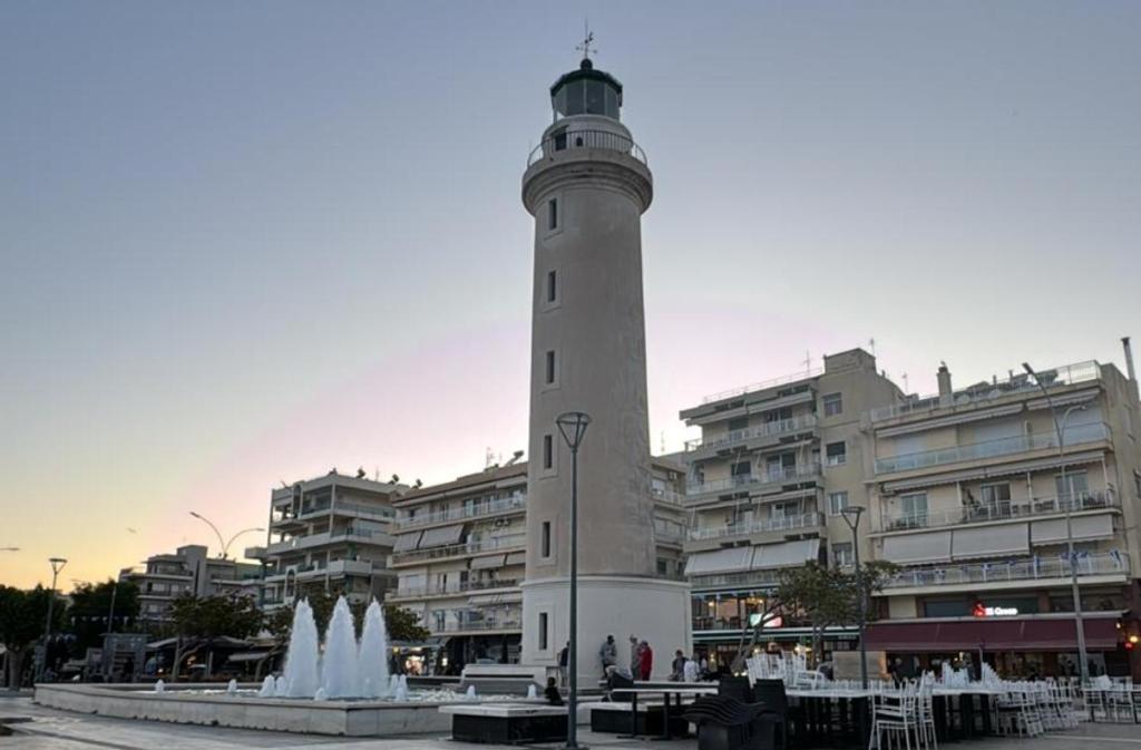 a lighthouse in front of a building with a fountain at Angelina's Home and Spa Alexandroupolis in Alexandroupoli