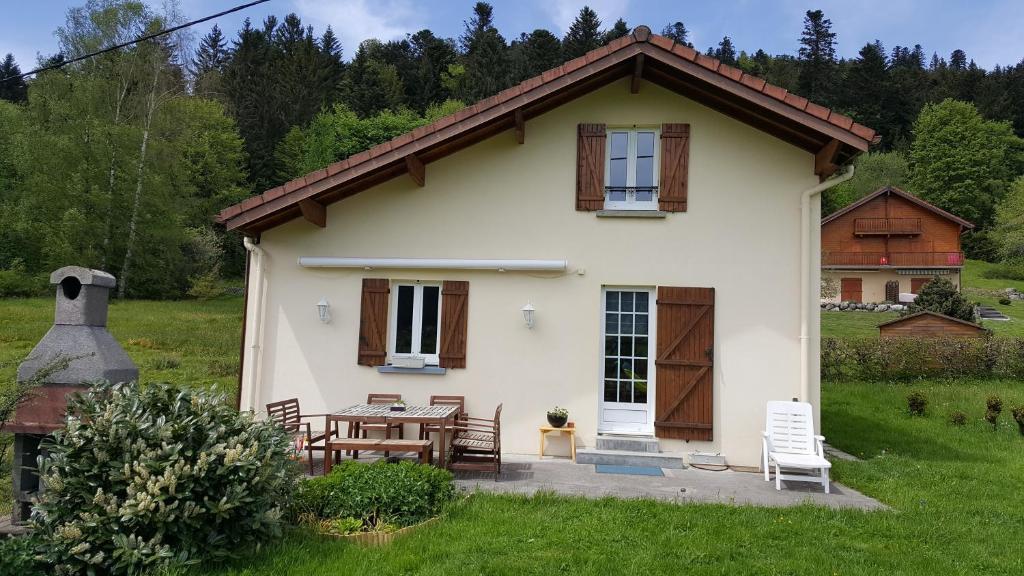 una pequeña casa blanca con una mesa en el patio en Gîte Noa, en Xonrupt-Longemer