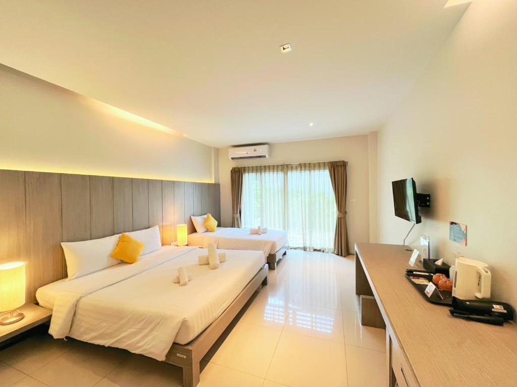 a hotel room with two beds and a television at Phuketa - SHA Extra Plus in Phuket Town