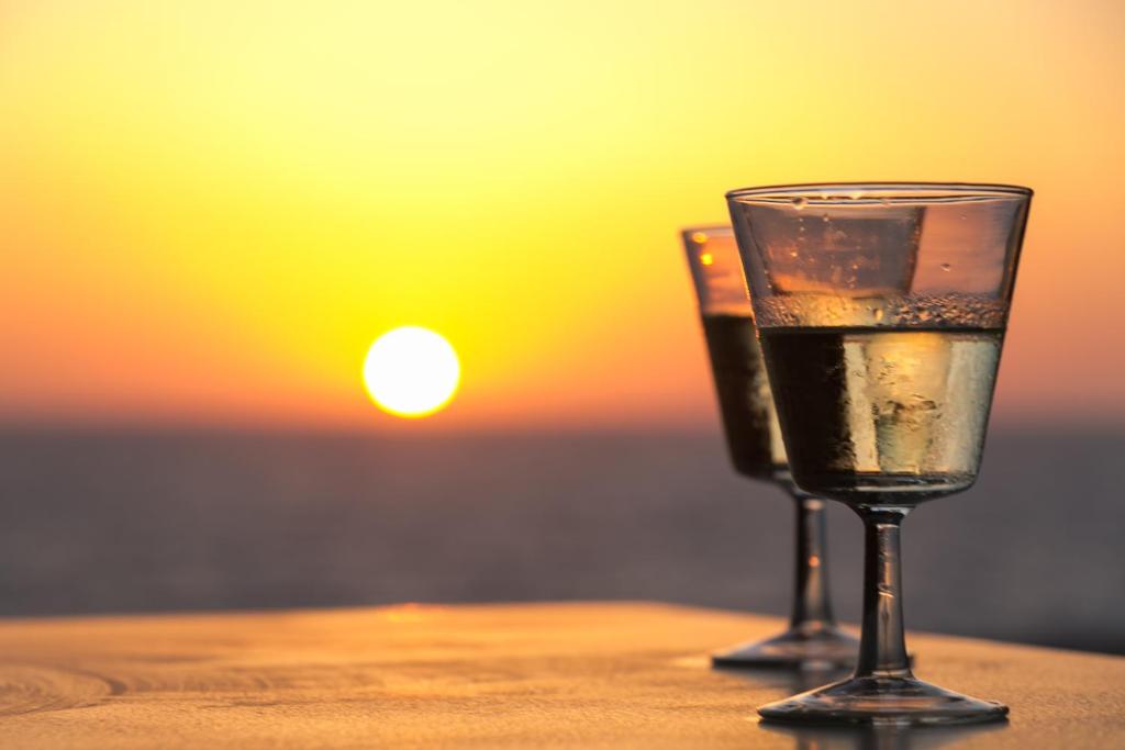 a glass of wine sitting on top of a table at Alpha Studios in Arkasa