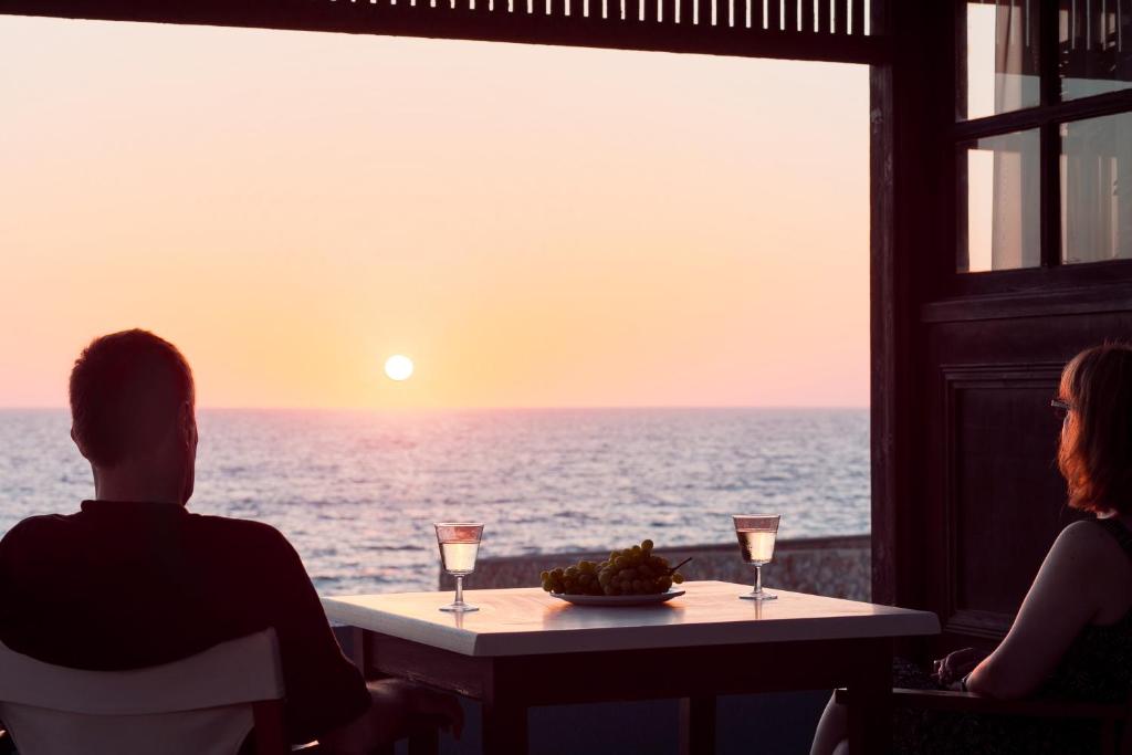 a man and woman sitting at a table looking out at the ocean at Alpha Studios in Arkasa