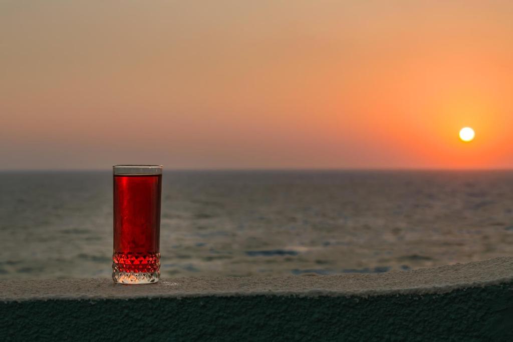 a red glass sitting on a ledge near the ocean at Alpha Studios in Arkasa