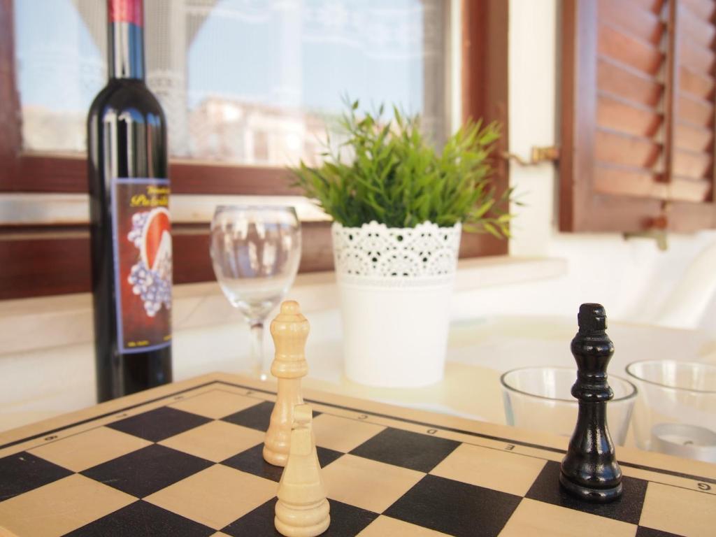 un tablero de ajedrez y una botella de vino y una copa en Bunari Apartments, en Tribunj