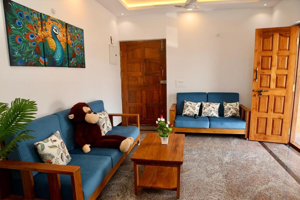 - un salon avec un ours en peluche assis sur un canapé bleu dans l'établissement 2BHk Peacock in North Goa, à Porvorim