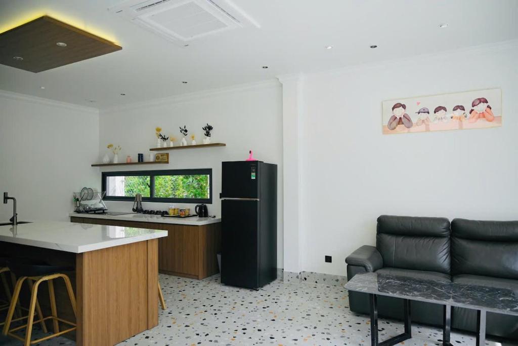 une cuisine avec un réfrigérateur noir et un canapé dans l'établissement Biển tôm ốc homestay hồ bơi & BBQ garden, à Xóm Bình Nguyên