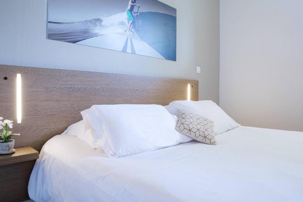 a bed with white pillows and a picture on the wall at Comfort Aparthotel Cannes Mandelieu in Mandelieu-la-Napoule