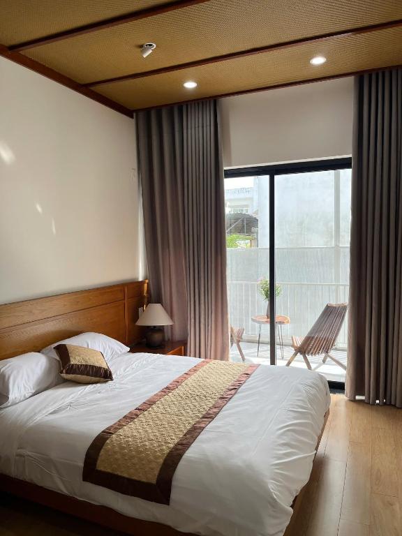 a bedroom with a large bed and a balcony at Madam Thu House in Hue