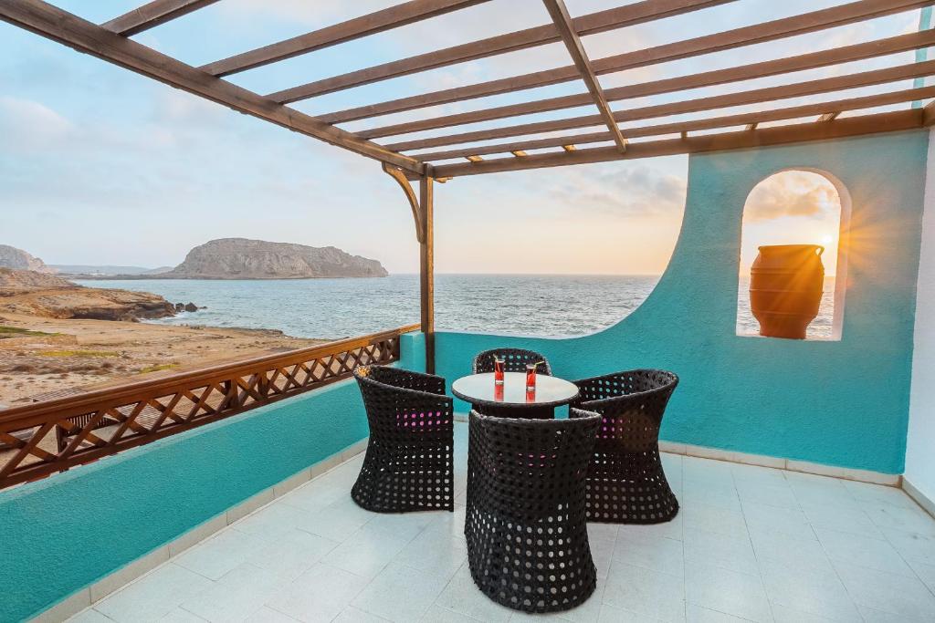 a table and chairs on a balcony overlooking the ocean at Alpha Studios in Arkasa