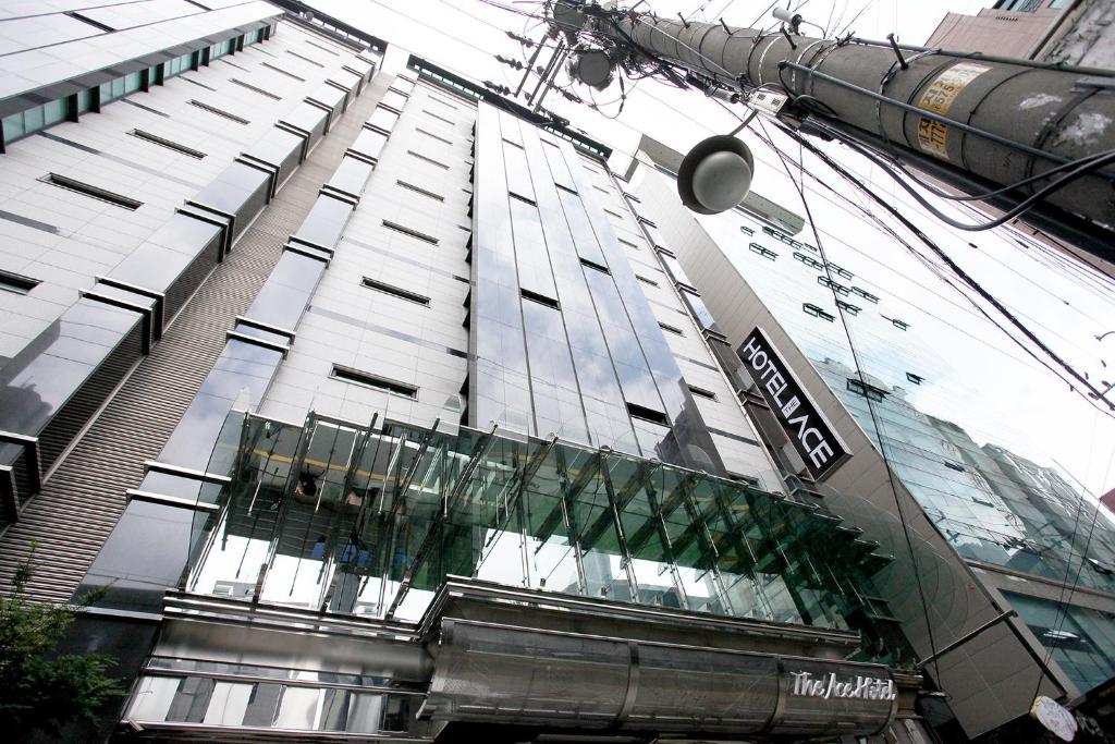 a tall glass building with a glass revolving door at The Ace Hotel in Seoul