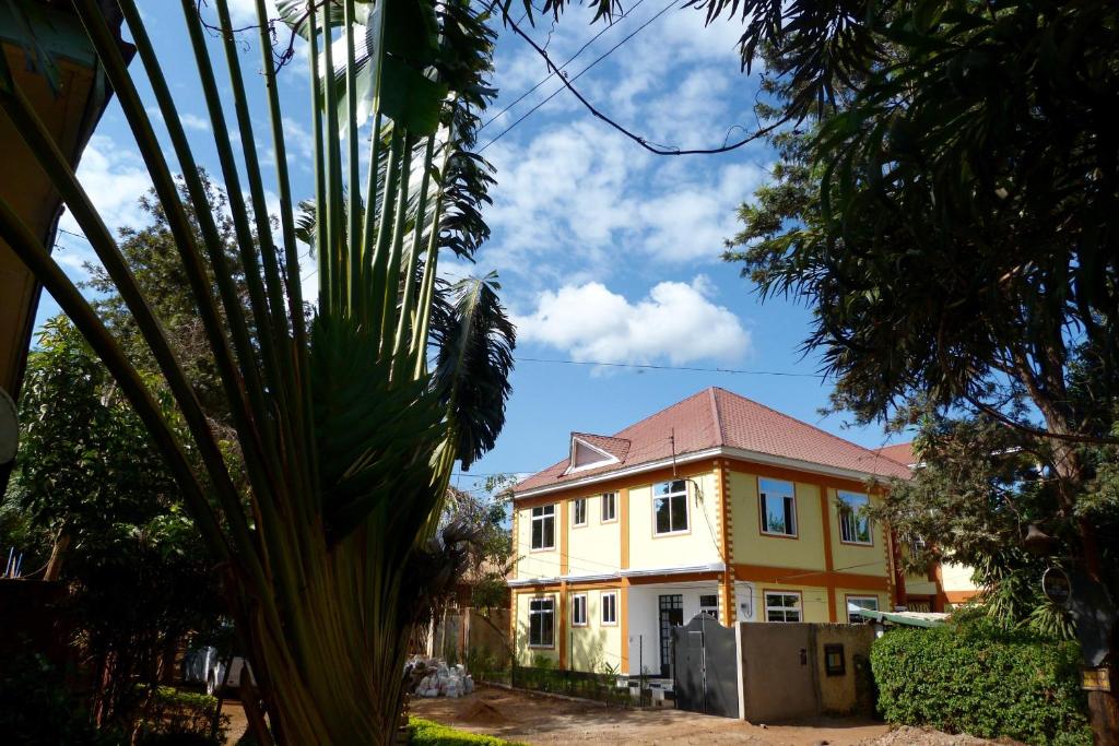 a yellow house with a palm tree in the foreground at Rafiki Backpackers & Guesthouse in Moshi
