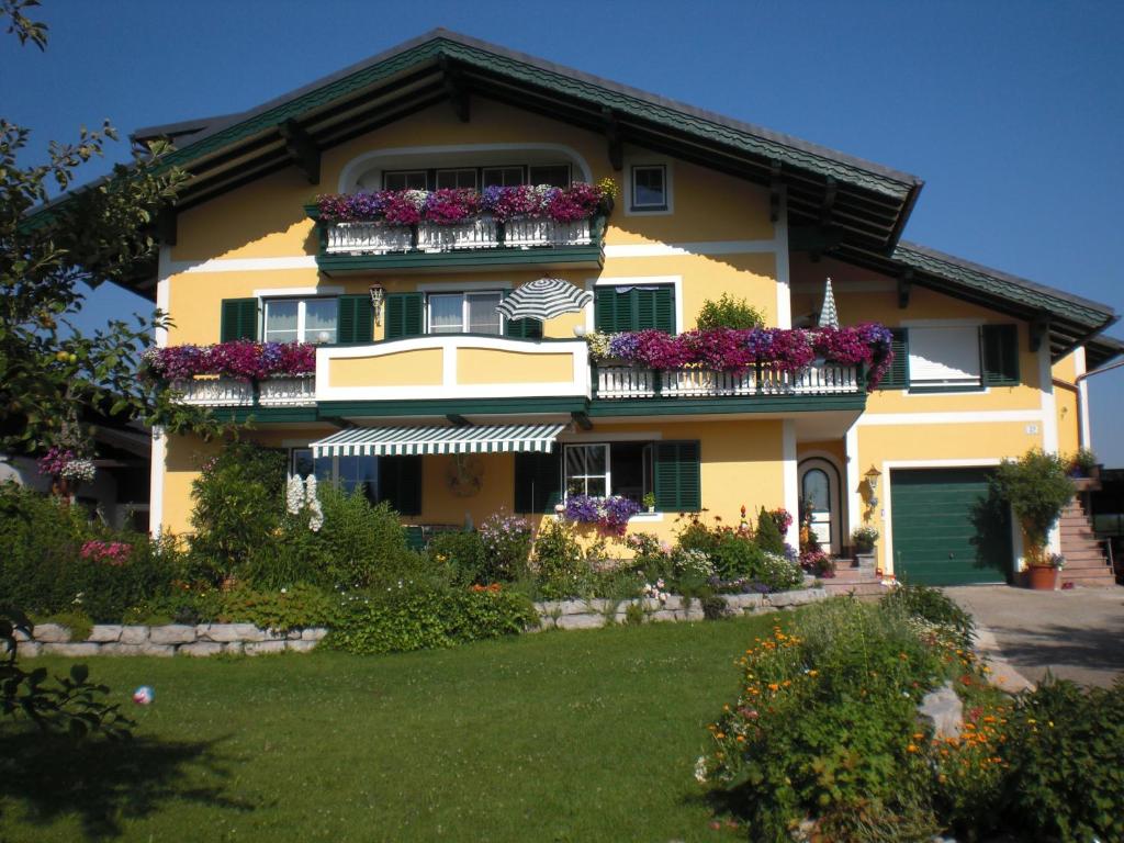 ein gelbes Haus mit Blumen auf den Balkonen in der Unterkunft Ferienwohnung Winklhofer in Mondsee