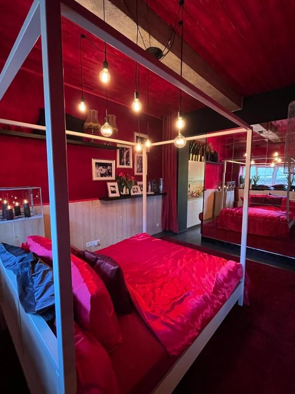 a red room with a large bed with red sheets at Romantic house with hot tub in Poelkapelle