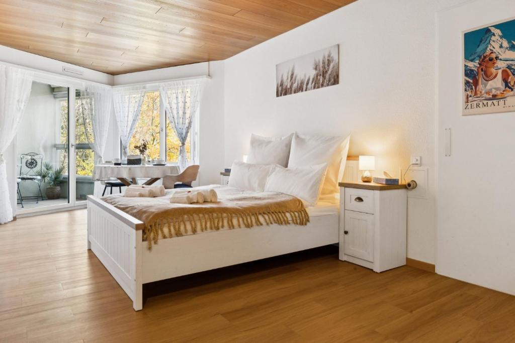 a white bedroom with a bed and a table at Lake View Studio 1 - 2 Personen I See - Bergsicht I 40" Smart TV I Dusche, Fahrstuhl und Parkplatz in Ingenbohl