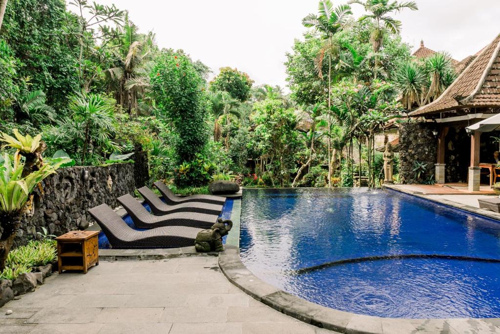 a swimming pool with two lounge chairs next to a house at Dewangga Suite in Ubud