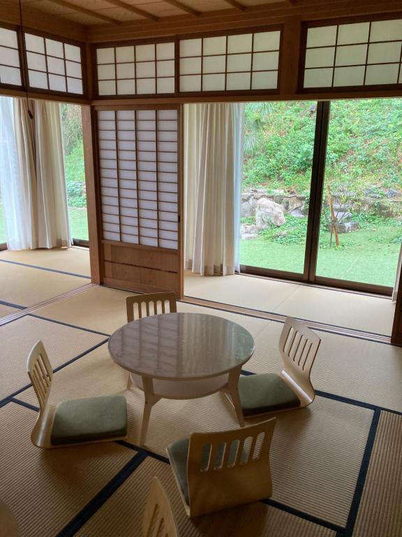 a living room with a table and chairs and windows at ヴィラこんぴら Villa Konpira in Kotohira
