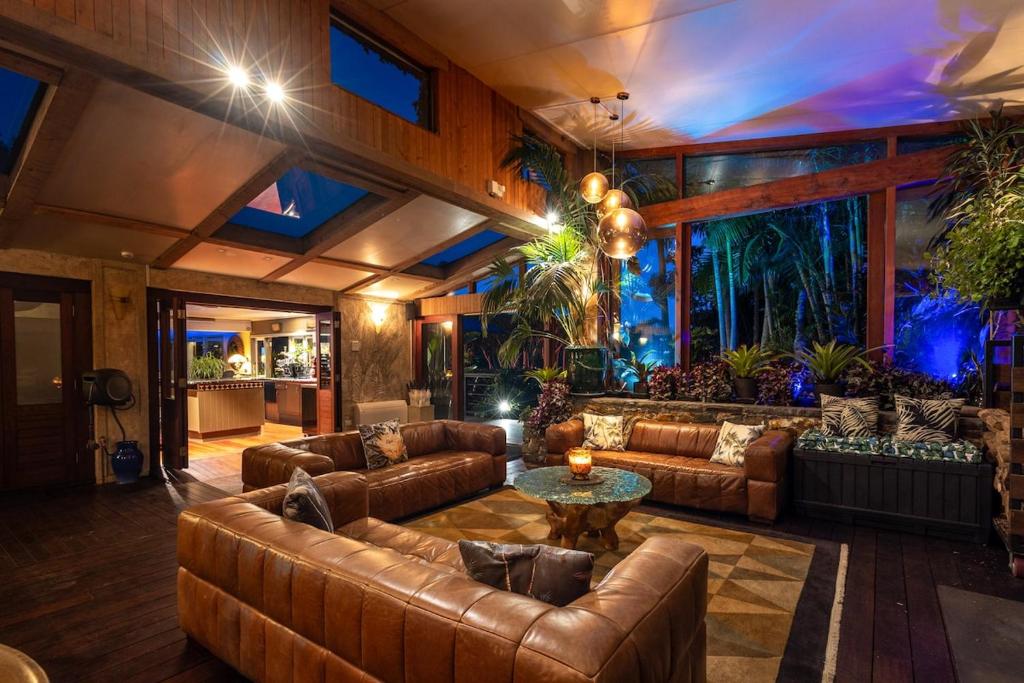 a living room with leather couches and a table at Kauri Springs Lodge still the same beautiful place but so so much better in Waiheke Island