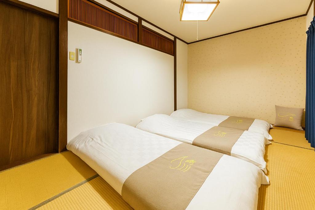 a small bedroom with two beds in it at 夏様四条大宮 四条大宮駅5分 京都市中心部 一棟一組貸切 広い庭付き一戸建て in Kyoto