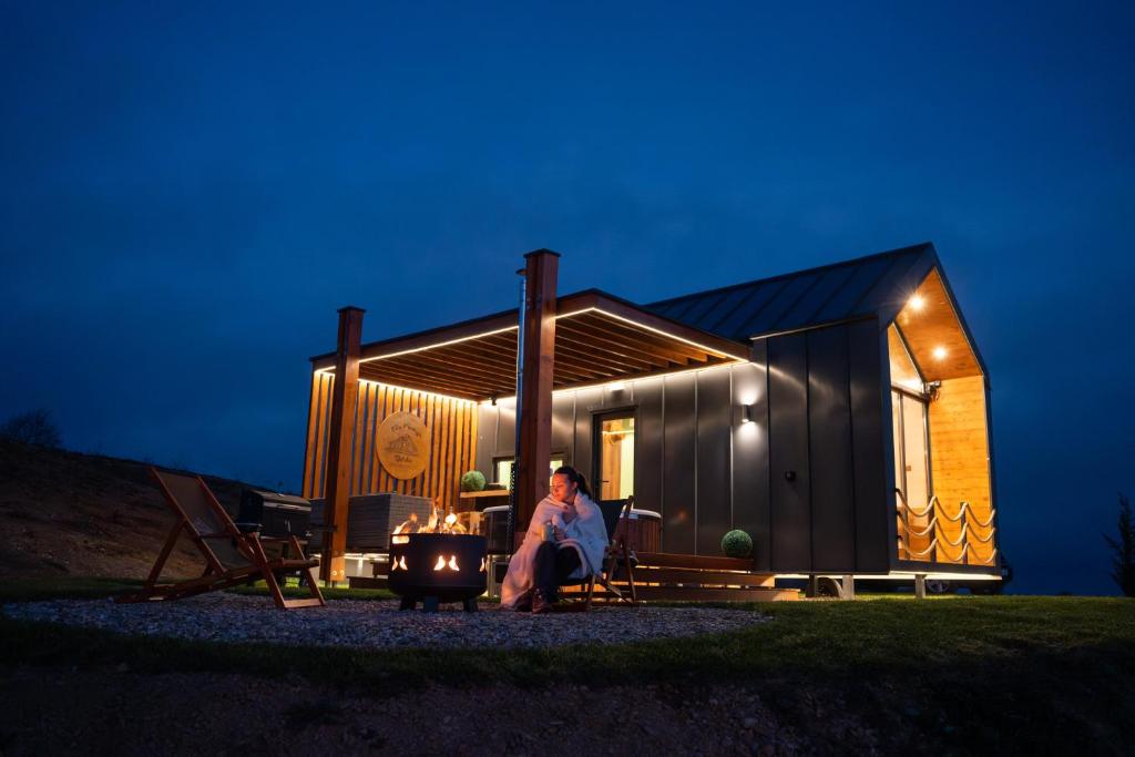 a woman sitting outside of a tiny house at night at Brvnara Vila Promaja in Kladovo